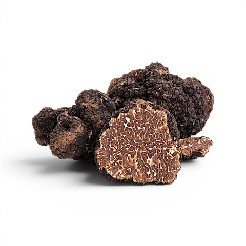 Trufas de Tuber uncinatum de Borgoña enteras y cortadas, mostrando interiores marrones marmoleados y maduros