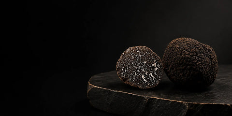 Fresh Black truffle – Tuber melanosporum – with its marbled interior displayed on dark stone