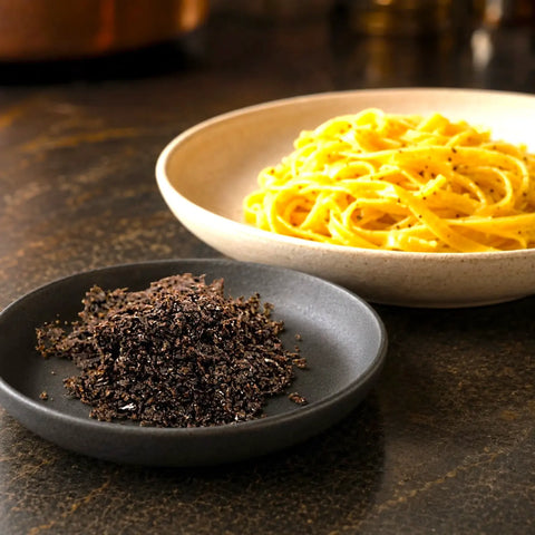 Fresh Tuber melanosporum pieces prepared beside a warm butter-based pasta dish