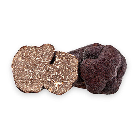 Trufas negras enteras y cortadas de Tuber melanosporum que muestran el interior oscuro con vetas marmoleadas
